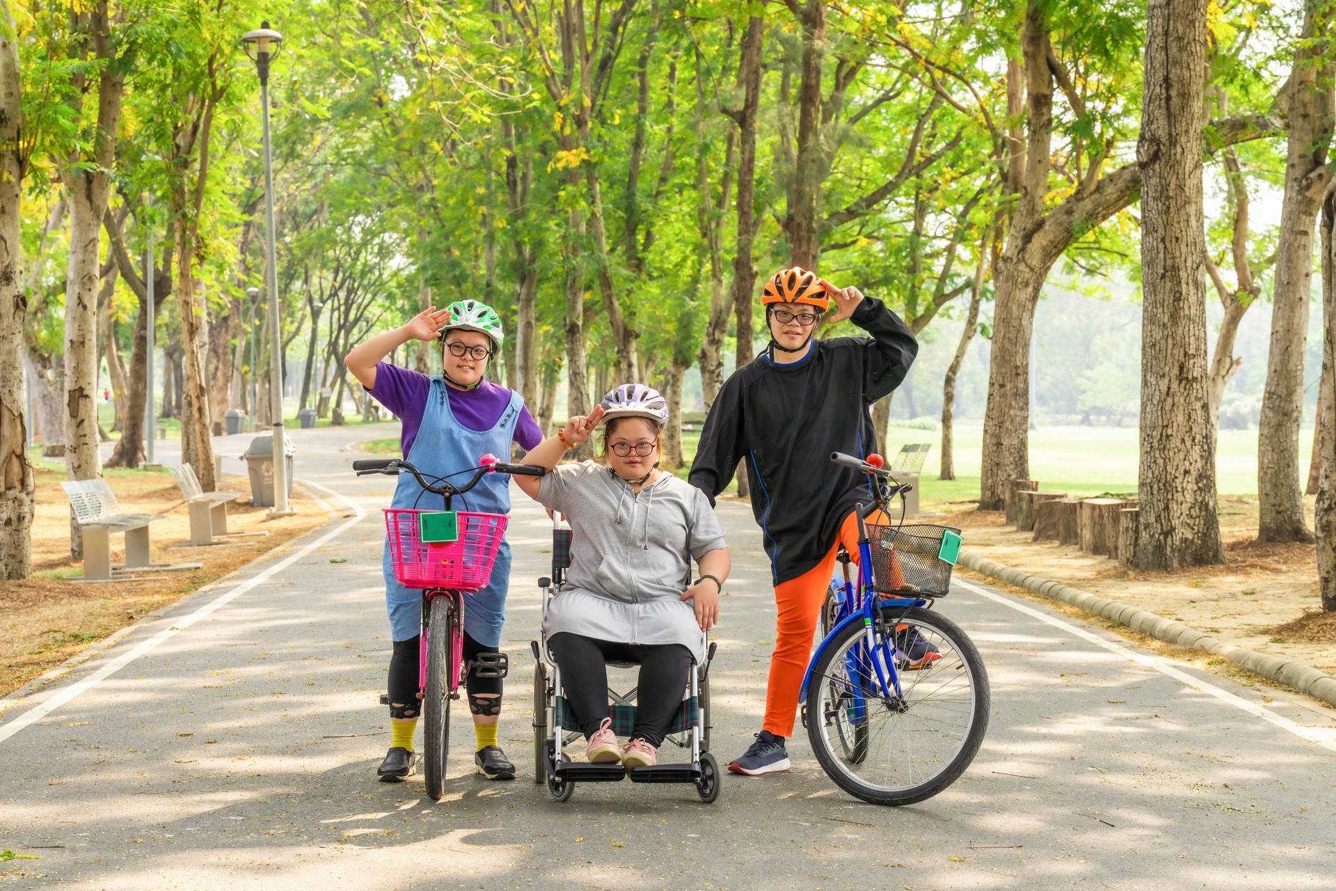 group of Asian friends with down syndrome riding bicycle and wheelchair