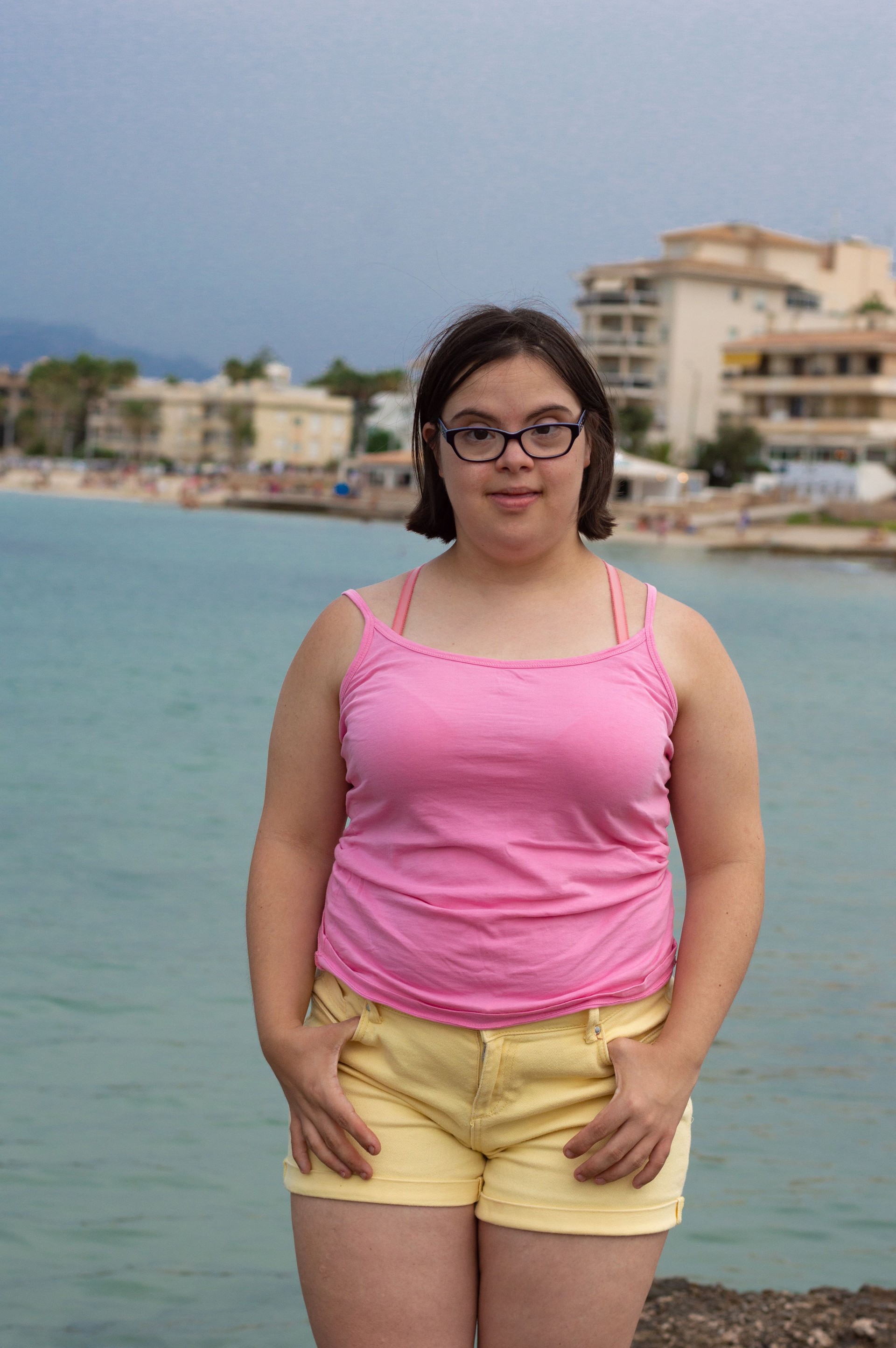 Charming woman with Down syndrome poses near the sea enjoying the summer